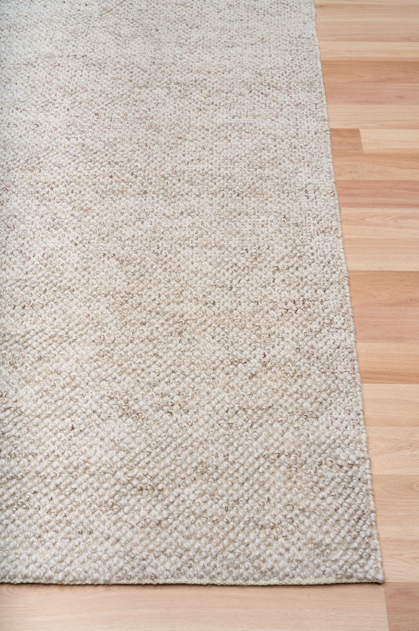 Light beige textured woven area rug with straight edge