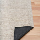 Light beige area rug with dark underside corner trim