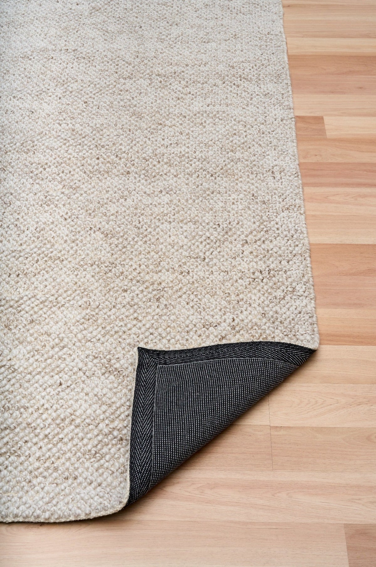 Light beige area rug with dark underside corner trim