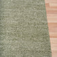 Olive green textured area rug with flat border along the corner