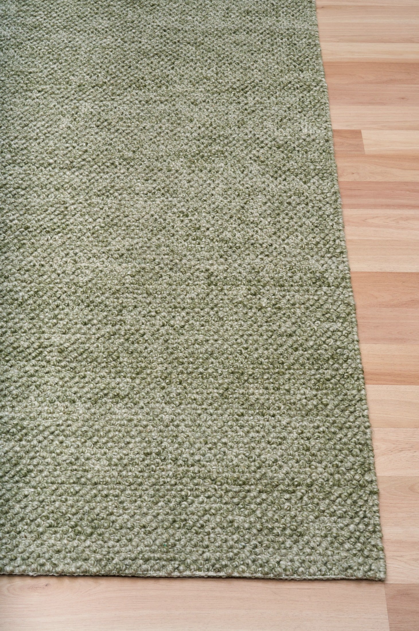 Olive green textured area rug with flat border along the corner