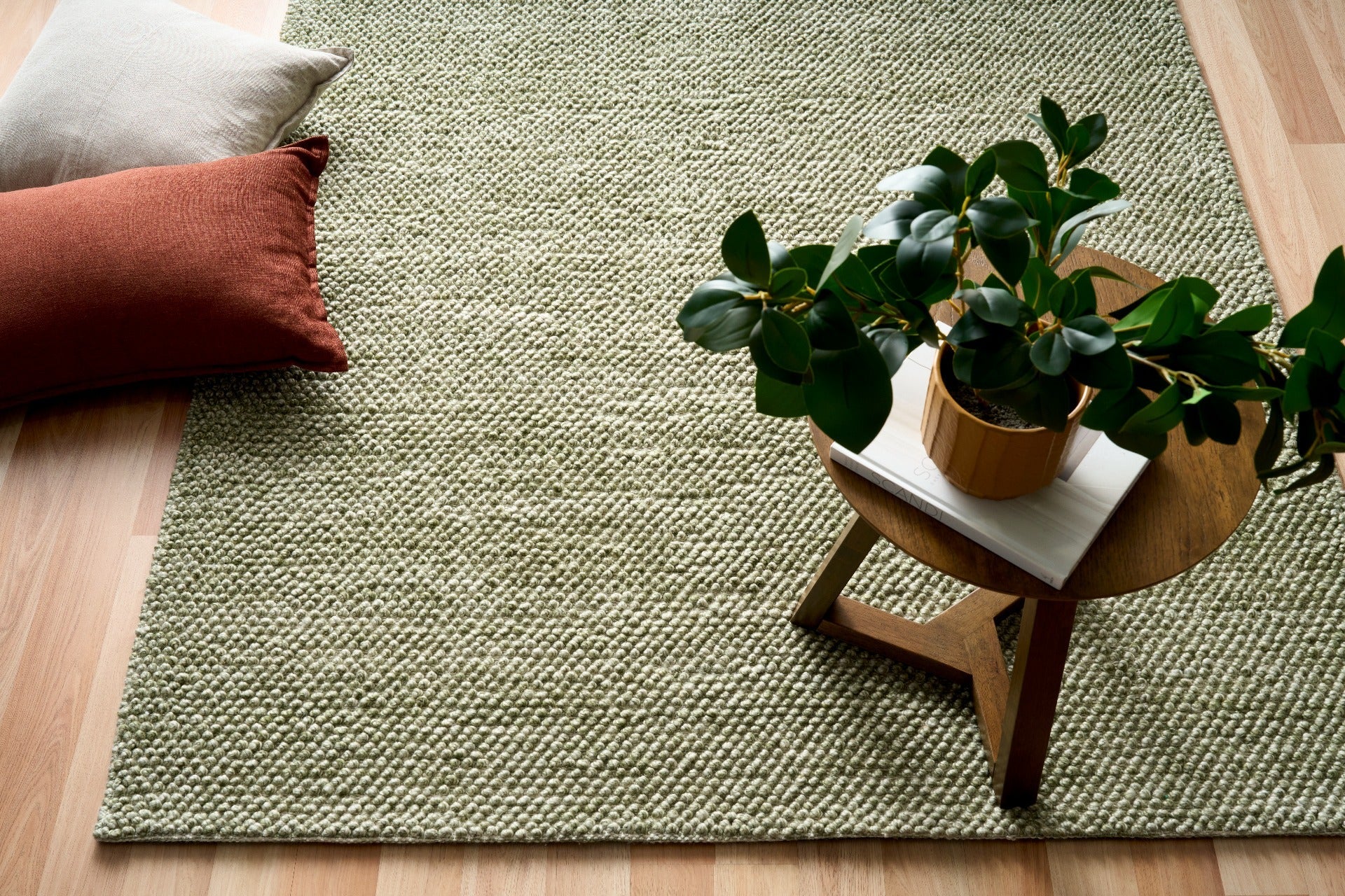 Olive green textured area rug laid on light wood flooring