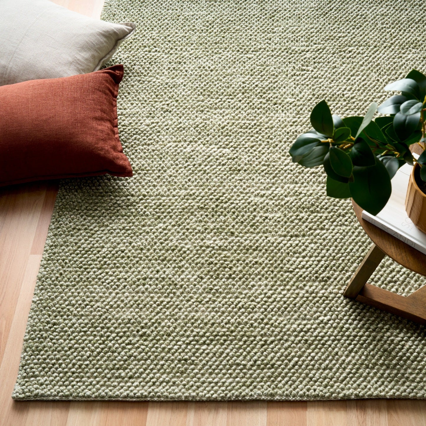 Olive green textured square area rug with visible corner and backing