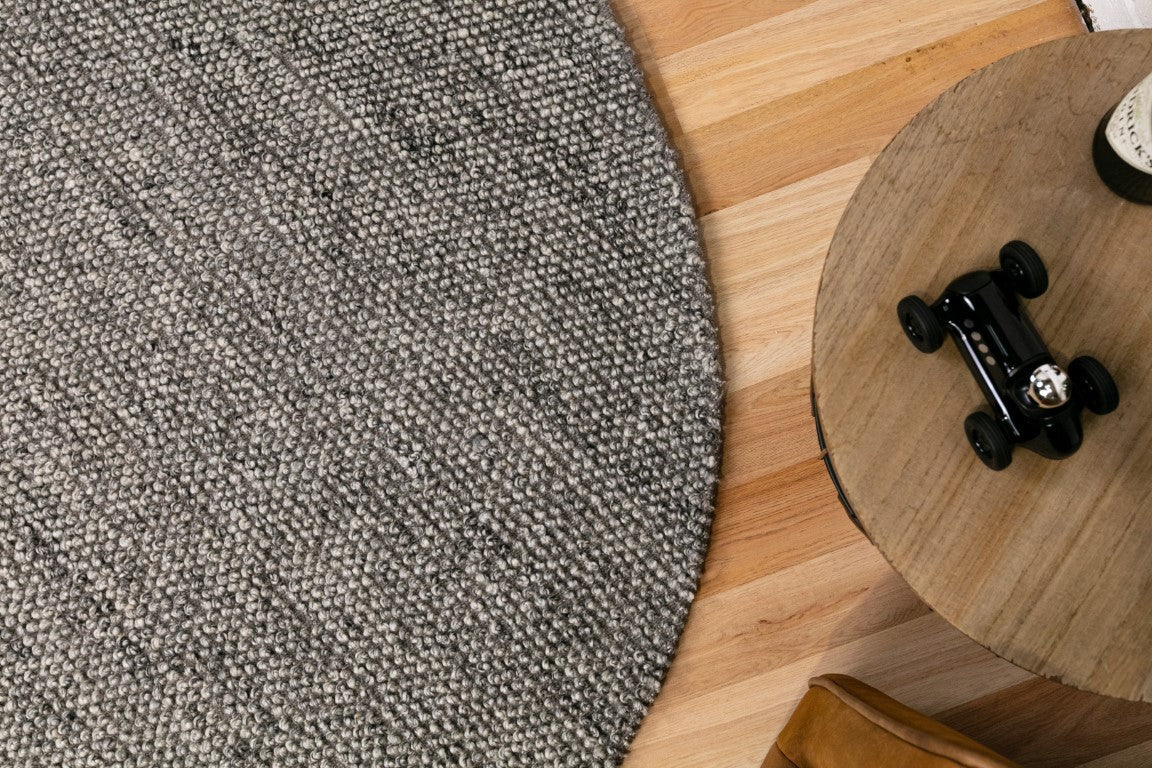 Grey textured round rug edge with speckled weave detail