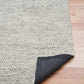 Grey textured area rug with dark backing visible at corner fold