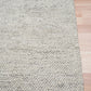 Grey textured area rug with dense loop texture and stitched edge