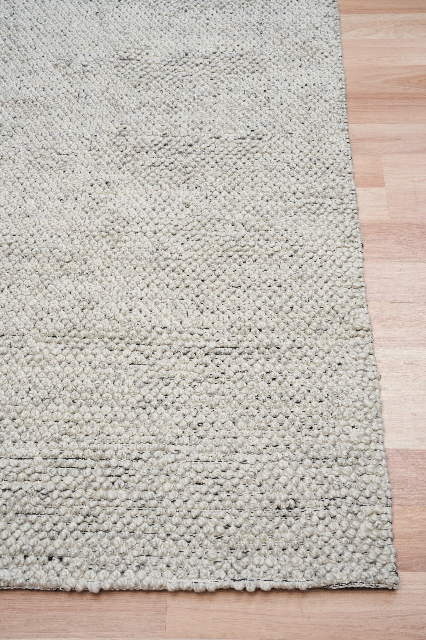 Grey textured area rug with dense loop texture and stitched edge