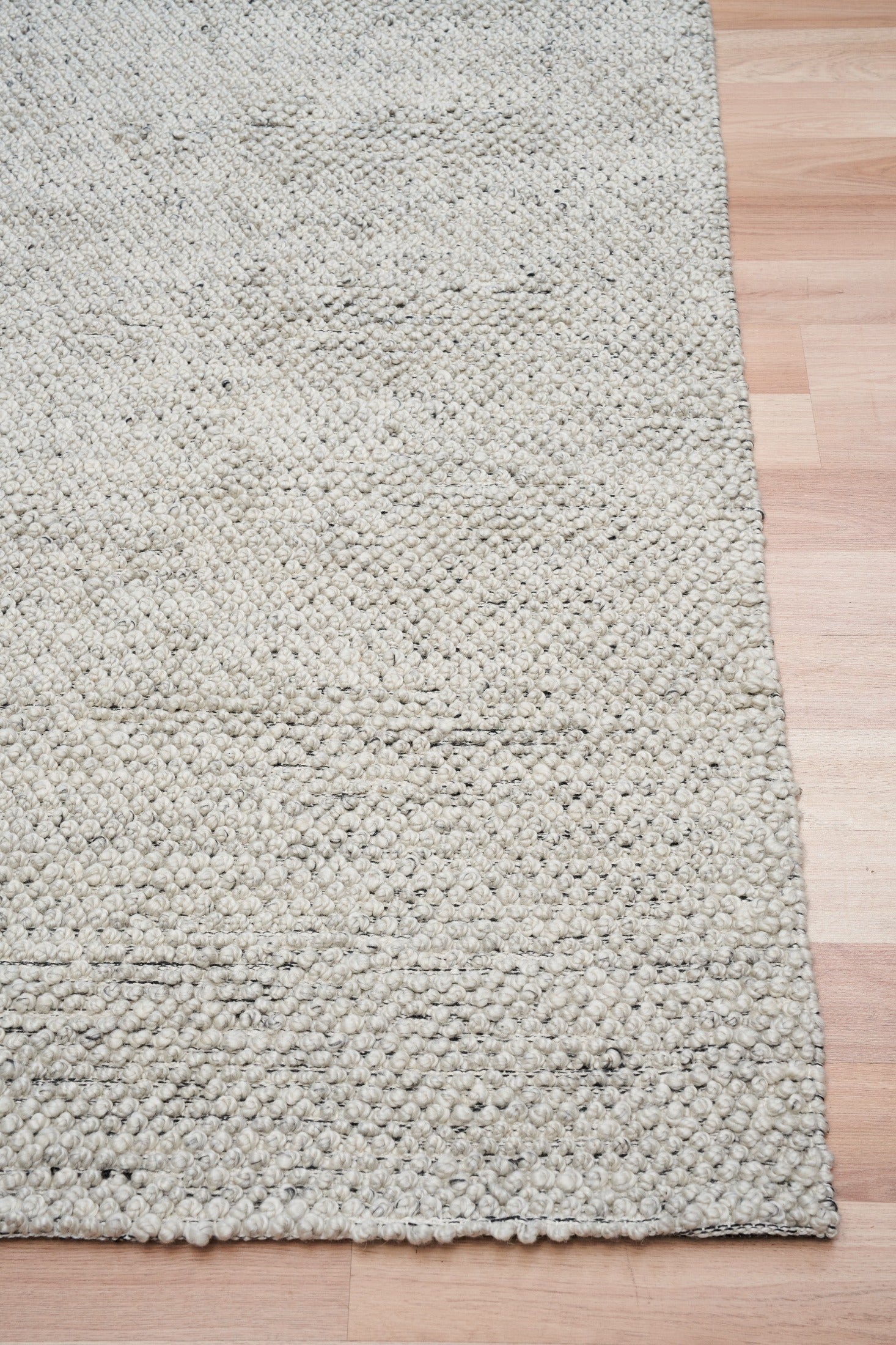 Grey textured area rug with dense loop texture and stitched edge
