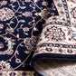 BALUCHI navy area rug corner with floral scrollwork and cream border trim