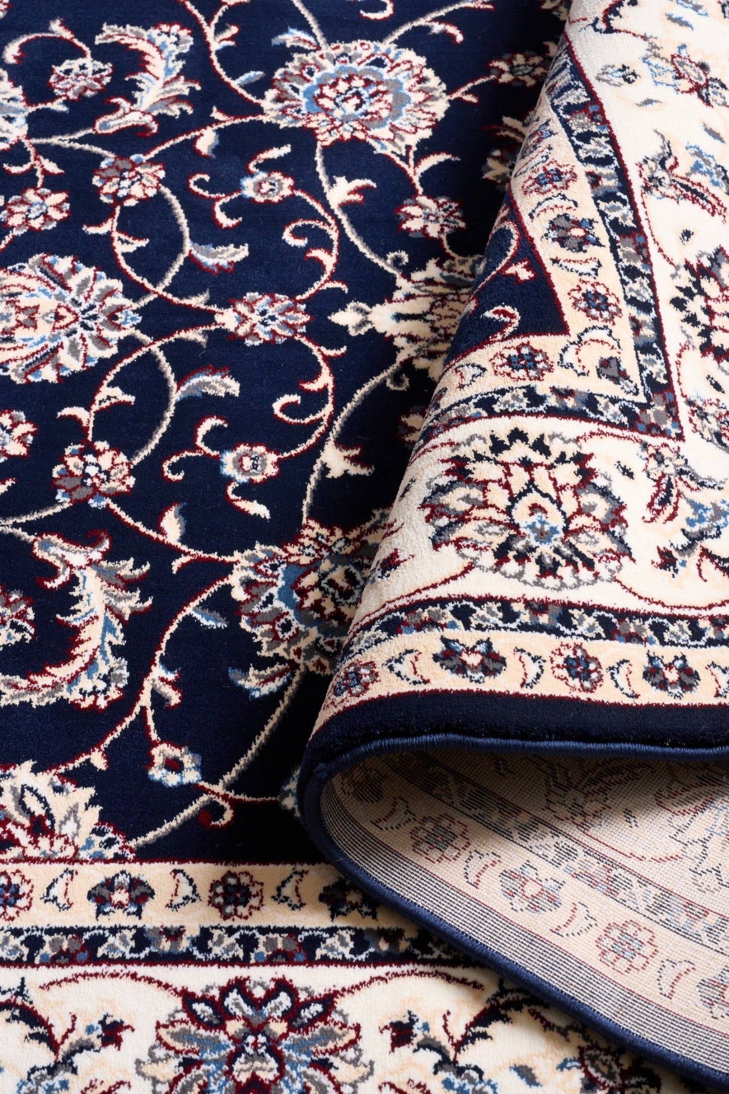 BALUCHI navy area rug corner with floral scrollwork and cream border trim