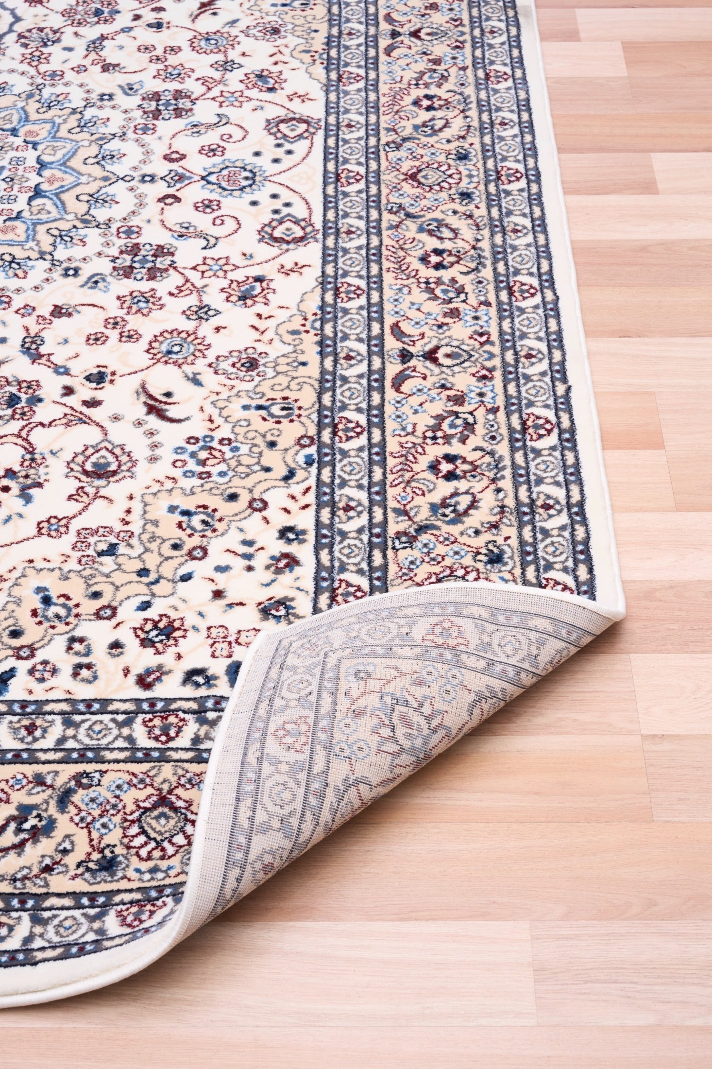 Ivory area rug corner with patterned border and folded edge view
