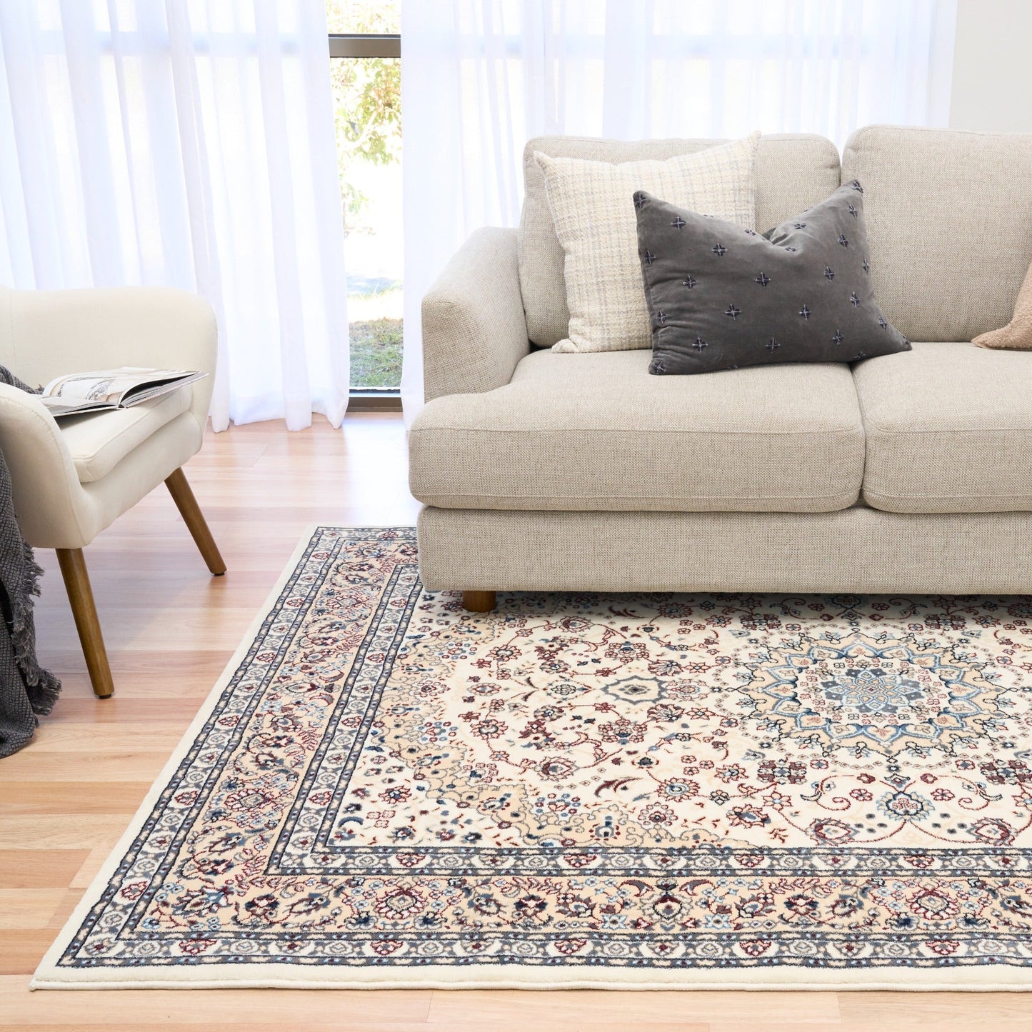 Ivory area rug laid out with ornate floral pattern and navy border stripe