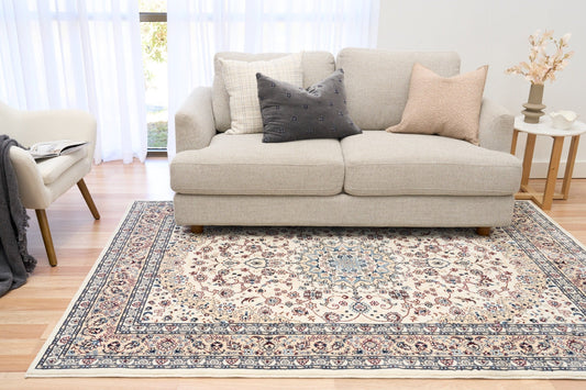 Ivory area rug with floral medallion pattern, blue border, and corner motifs