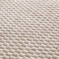 Close-up of light beige woven rug texture with tight looped fibers.