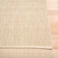 Light beige woven area rug edge with visible border and compact weave thickness.