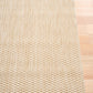 Light beige woven area rug corner detail showing thickness and tight weave.