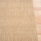 Beige woven rug corner with tight vertical rows of loop texture and edging