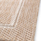 Beige rug edge with tight weave and stitched binding detail.