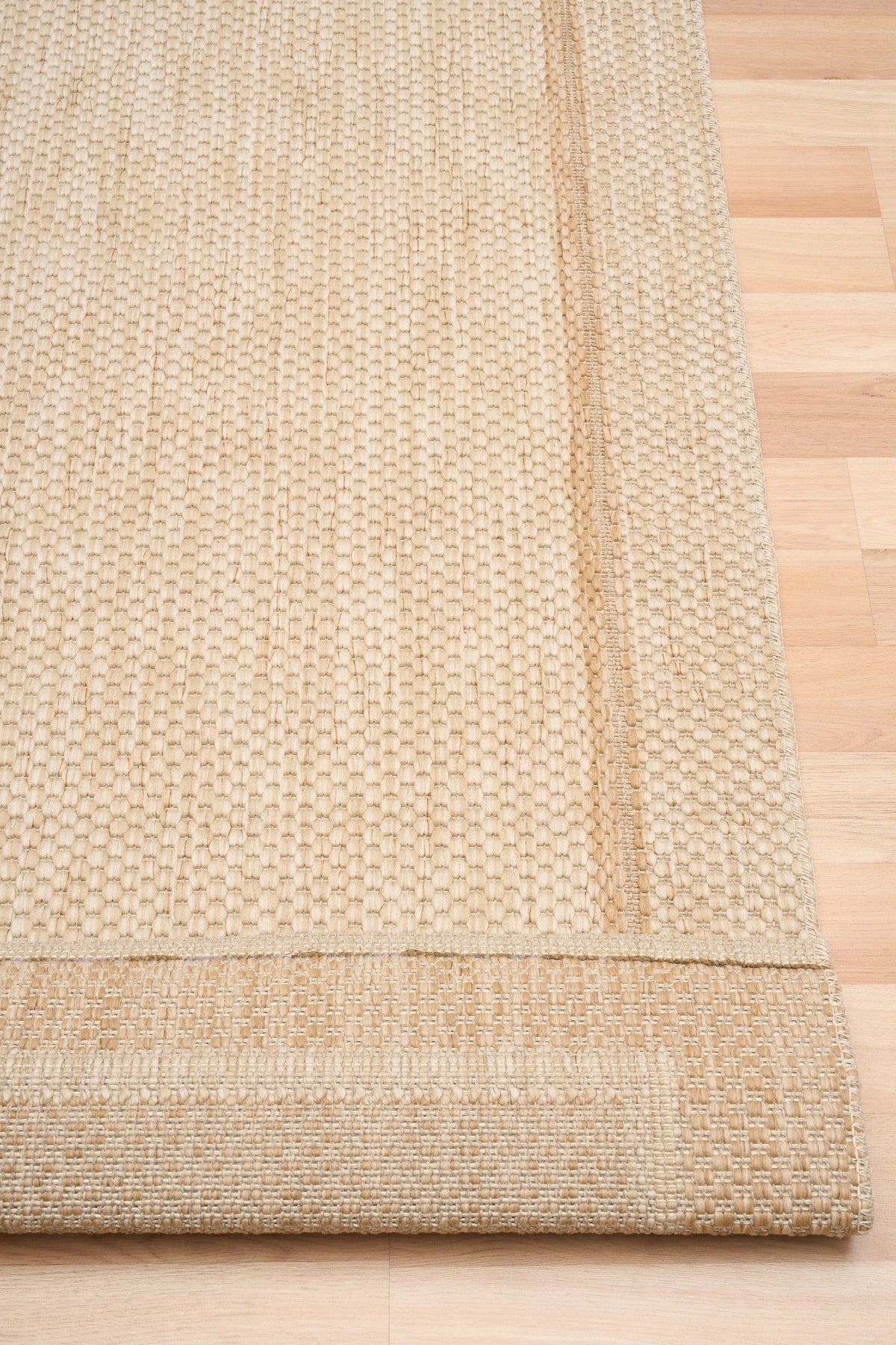 Beige rug corner showing layered edge and textured fabric close-up.