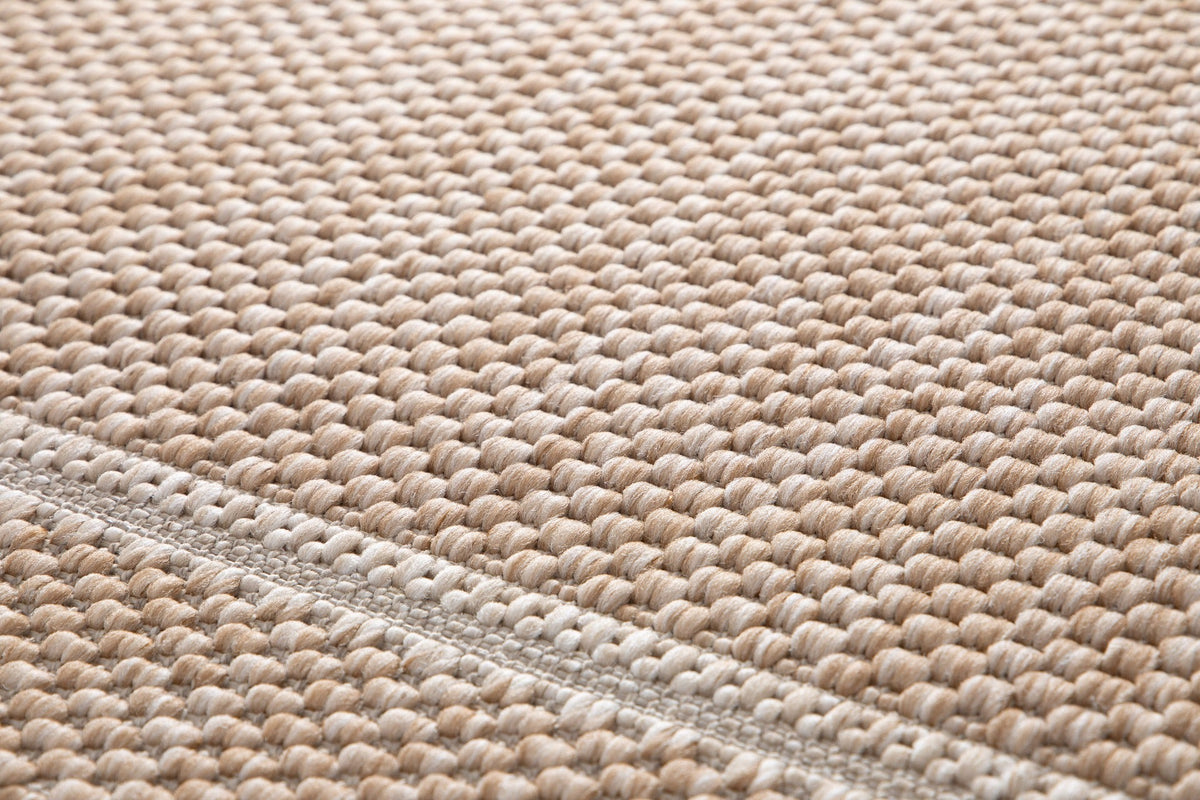 Beige woven area rug with braided edge detail along the border.