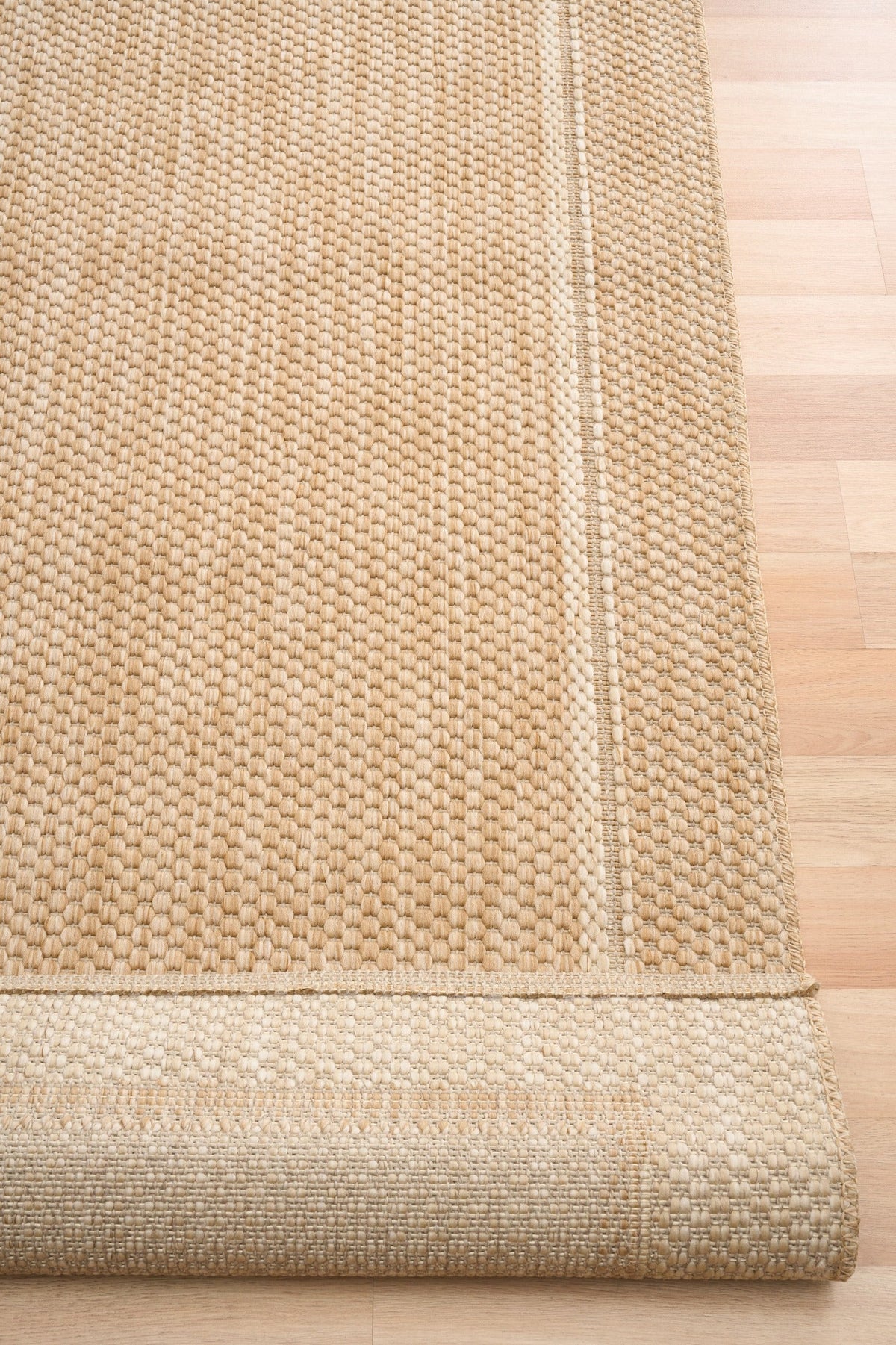 Beige textured area rug with visible edge binding and border trim