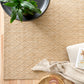 Beige woven rug with dense speckled texture and straight bound edge.