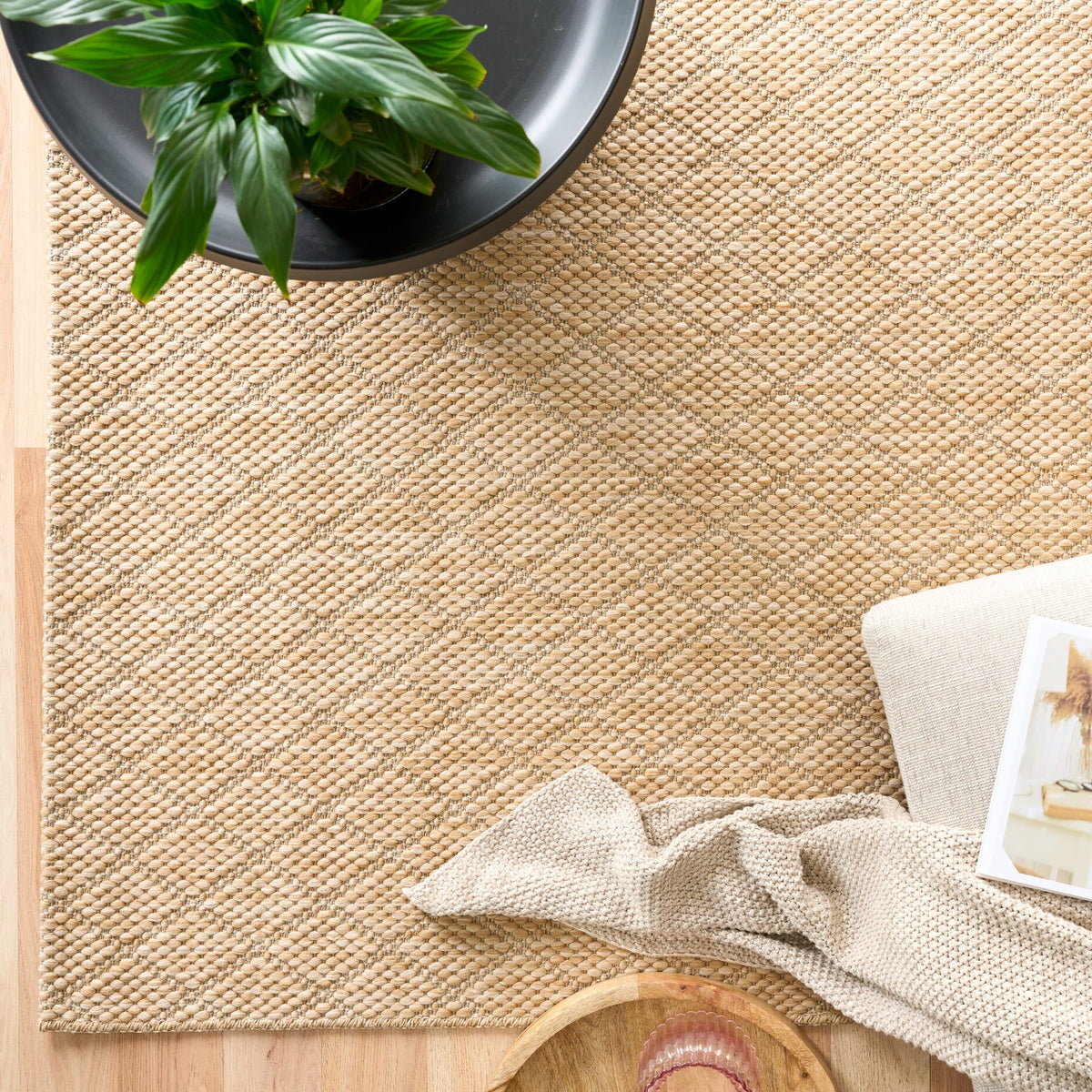 Beige woven rug with dense speckled texture and straight bound edge.
