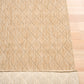 Beige woven rug corner with visible folded border and dense loop weave.