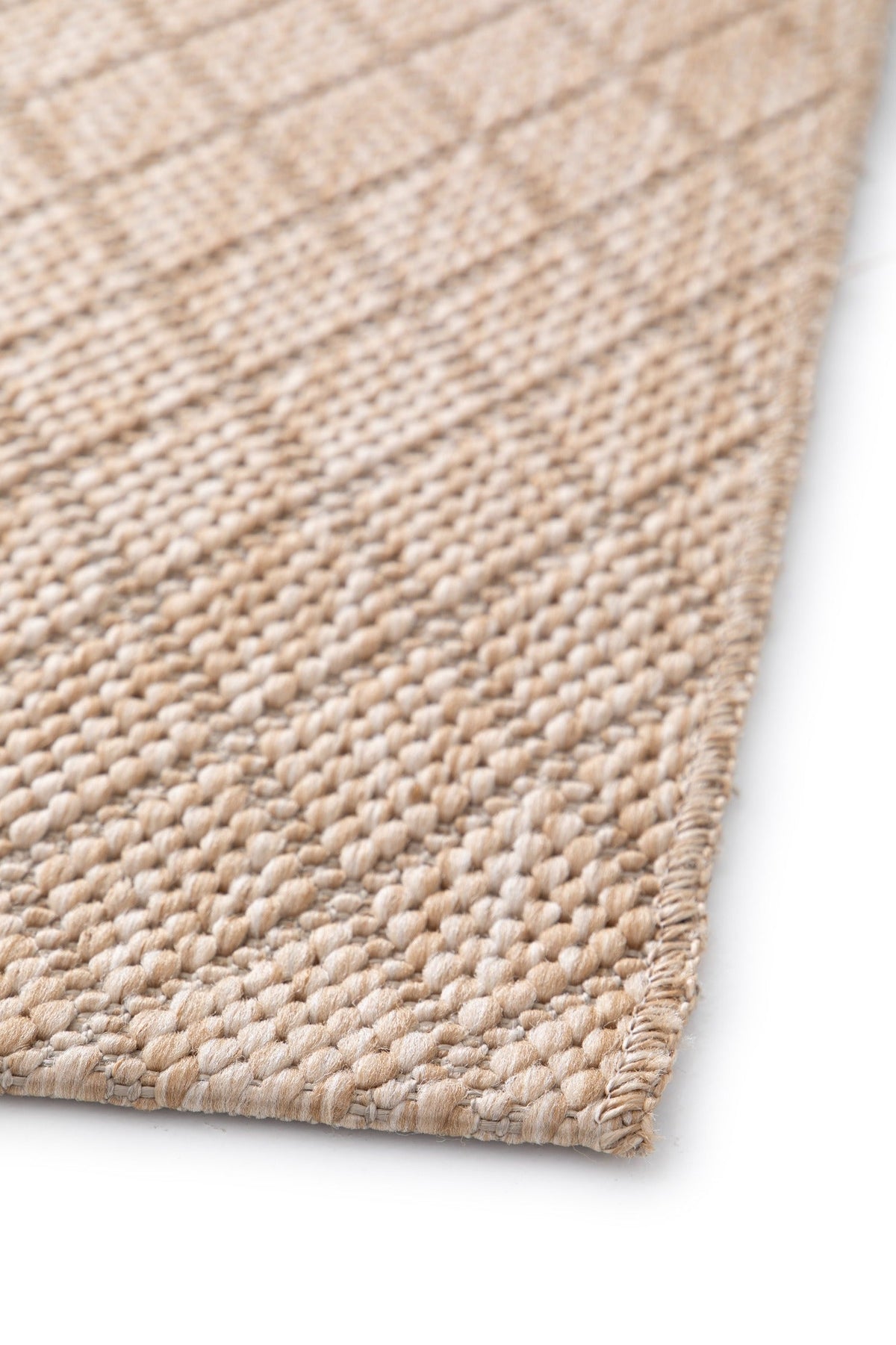 Beige woven rug corner with flat overlock edge and textured loop surface.