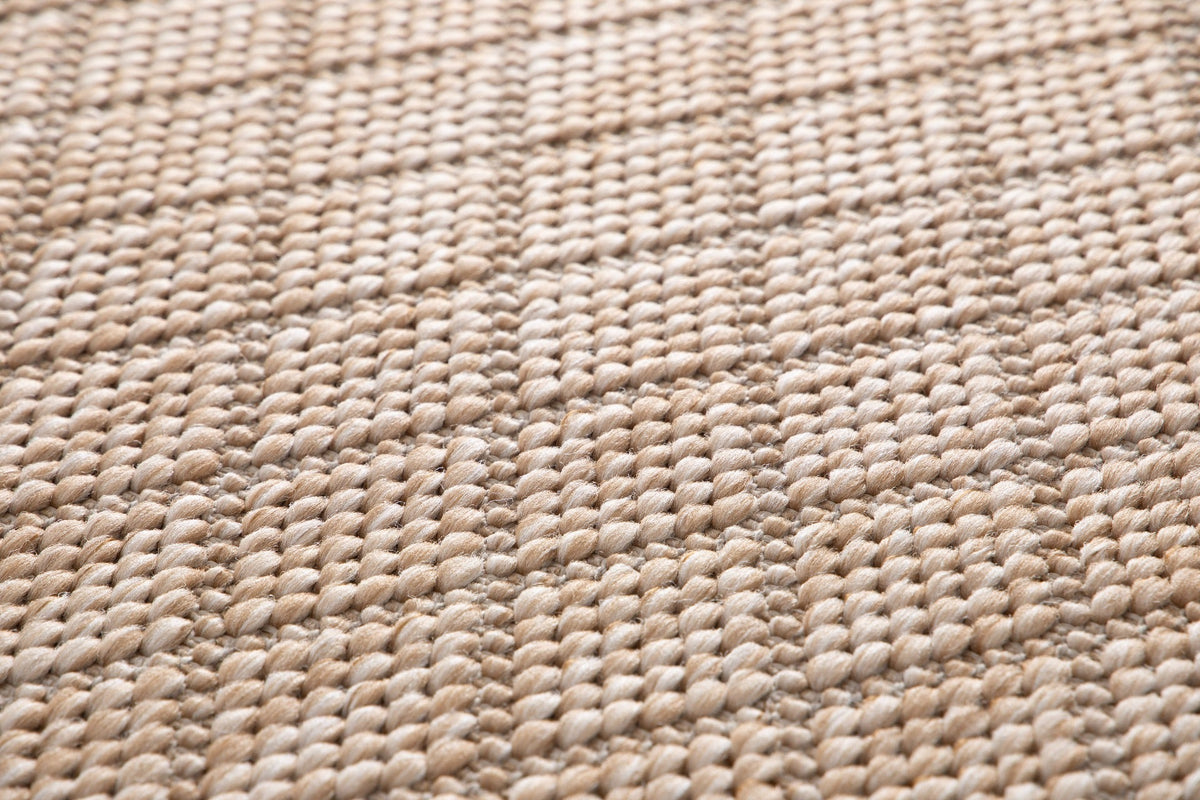 Close-up of beige woven rug texture with dense loop fibers.