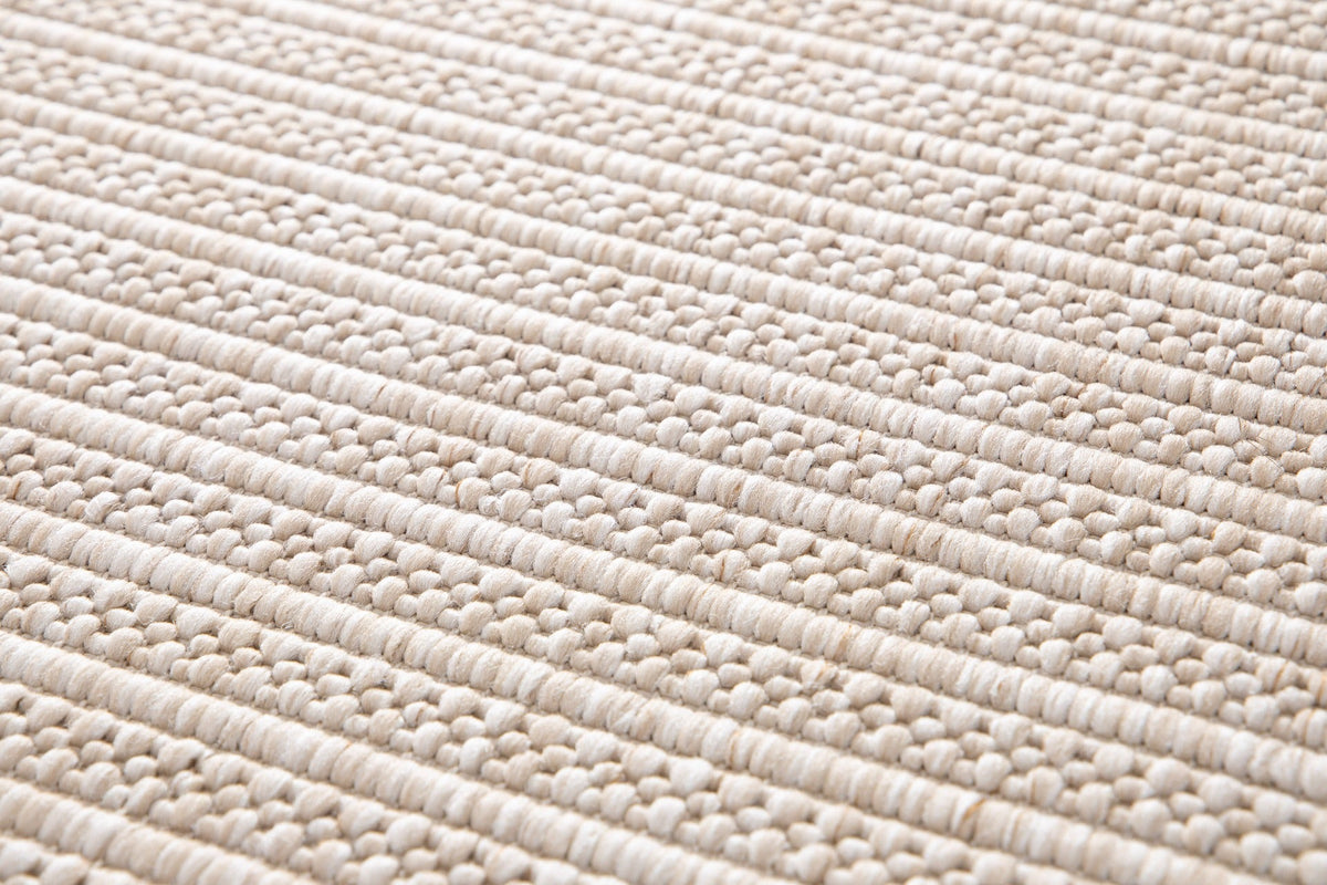 Beige woven rug close-up showing tightly packed looped fibers and ridged lines