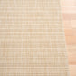 Beige woven area rug angled view showing dense striped grid pattern