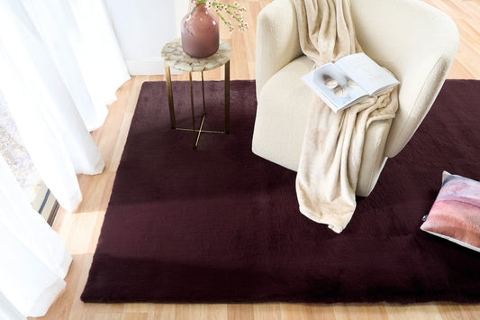 Rectangular dark plum area rug on light wood floor