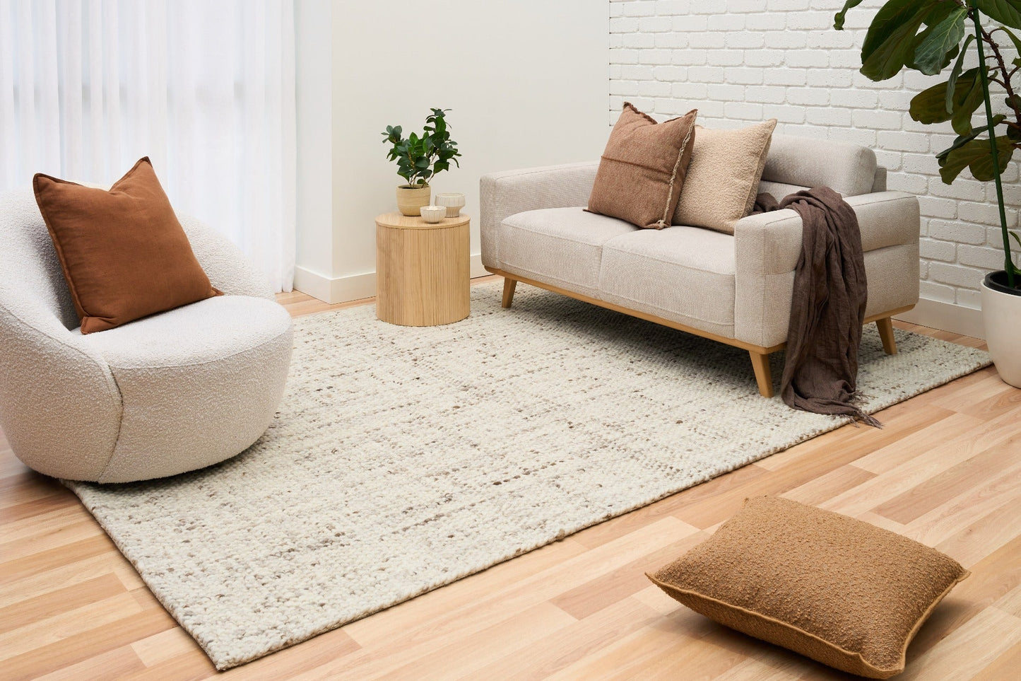 Beige textured area rug laid on light wood floor