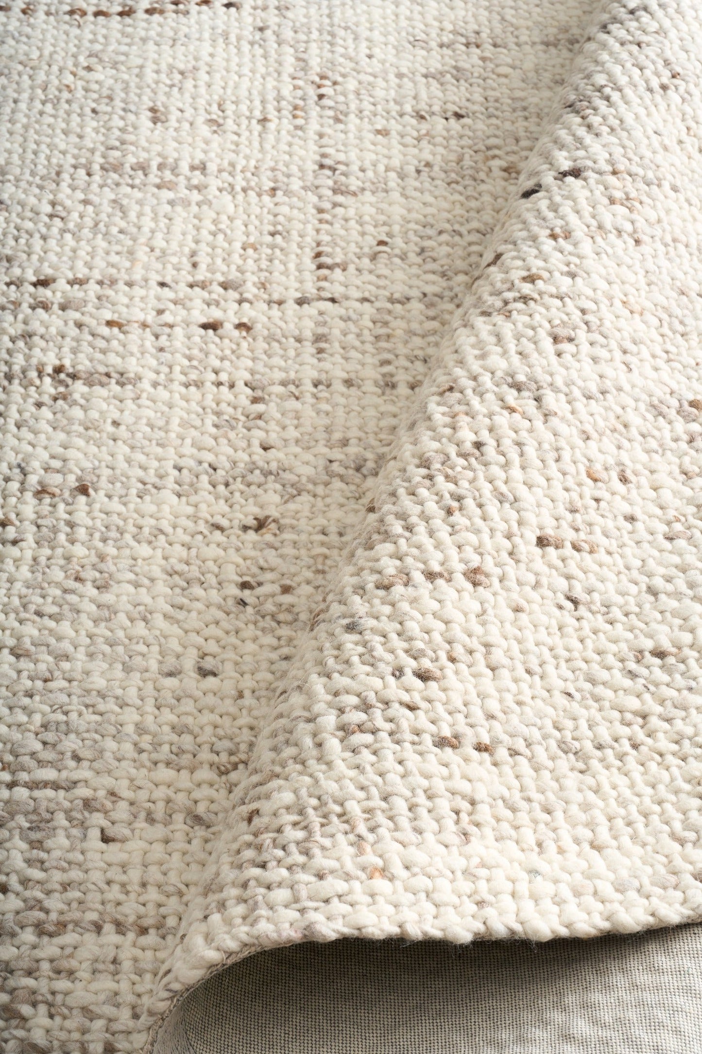 Beige textured area rug close-up with dense looped yarn and short fringe-free edge