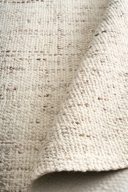 Beige textured area rug close-up with dense looped yarn and short fringe-free edge
