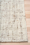 Beige textured area rug with stitched edge and mottled woven pattern