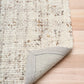 Beige textured area rug corner with visible woven backing and stitched border