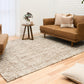 Large wool area rug on hardwood floor, beige with brown speckled texture