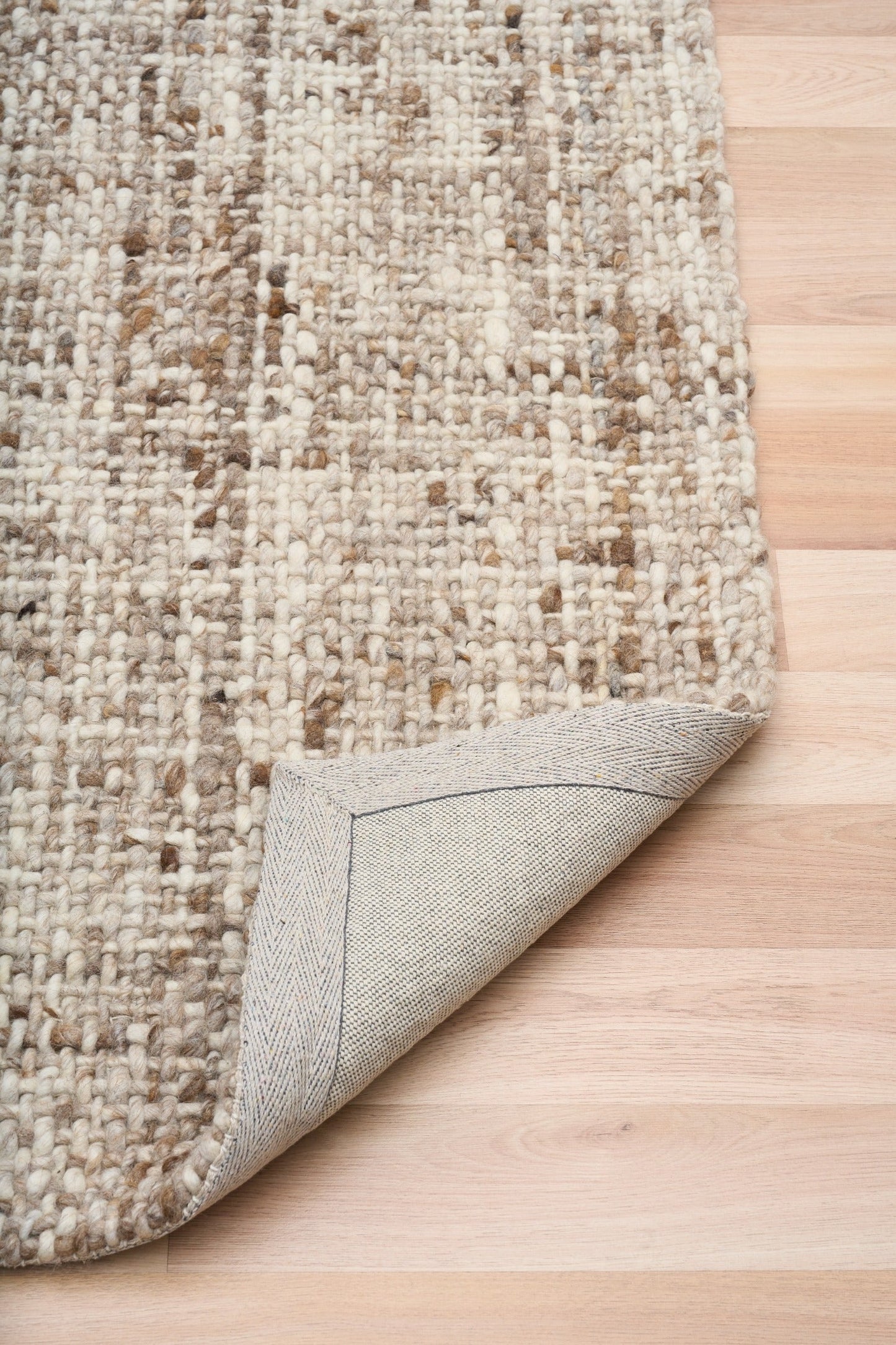 Wool rug with bound edge detail, beige underside on hardwood floor