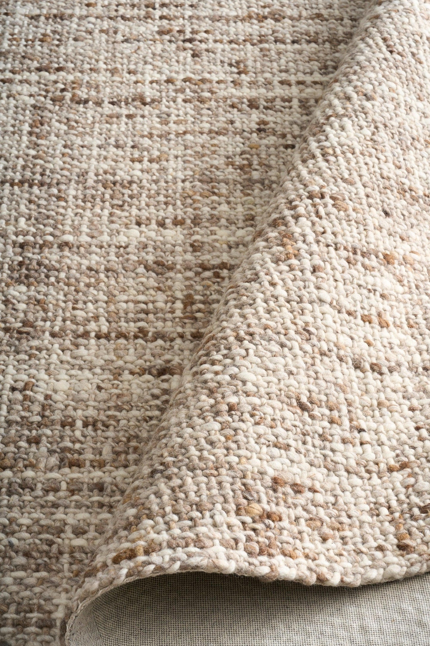 Wool rug corner detail, thick looped texture in beige and brown