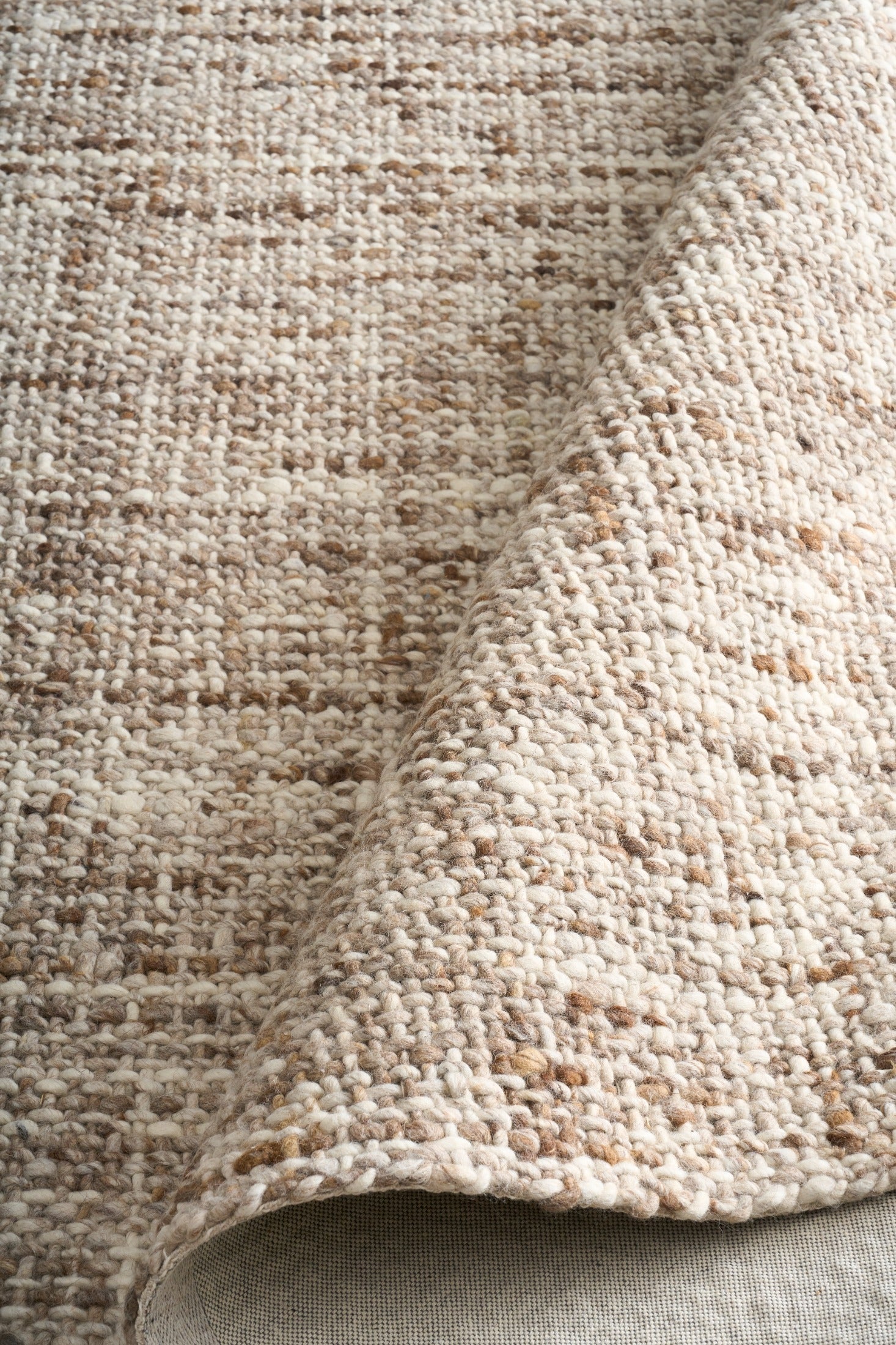 Wool rug corner detail, thick looped texture in beige and brown