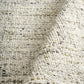 Ivory and light green textured area rug close-up with short pile and stitched edge