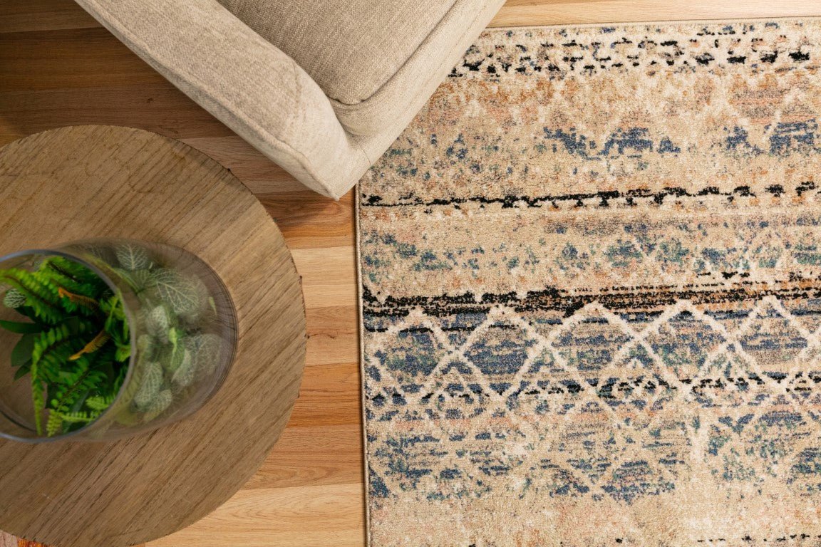 Blue and beige abstract area rug partially visible under light sofa and near round table