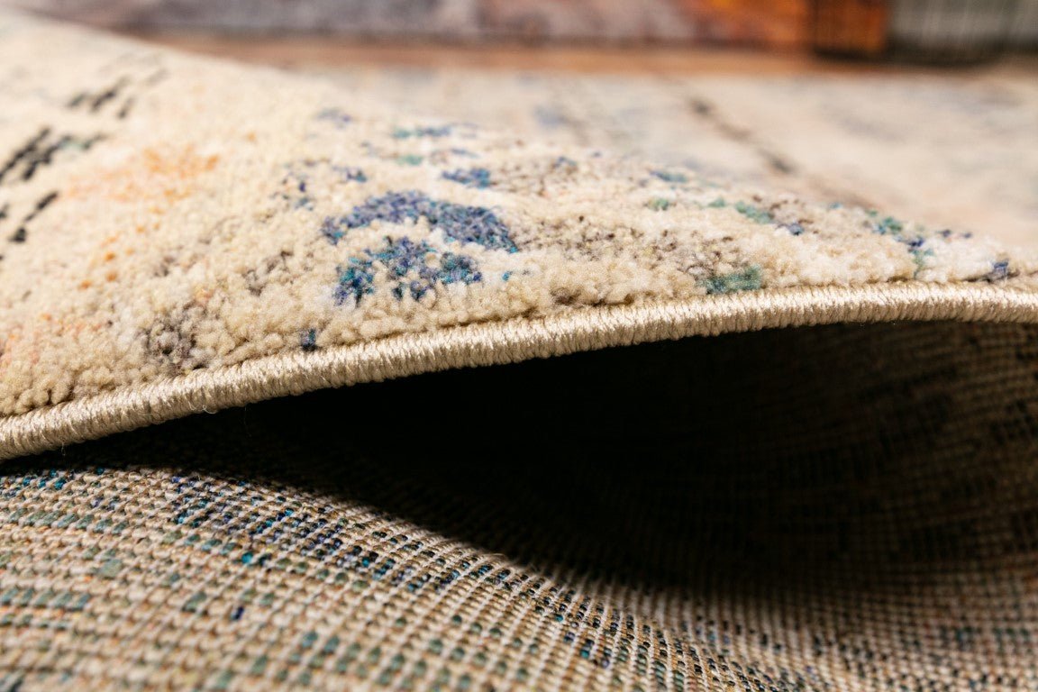 Rolled edge view of blue and beige rug with beige binding and low pile