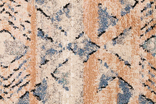 Close-up of rug pattern with rust, dark beige, and blue shapes and speckled texture.