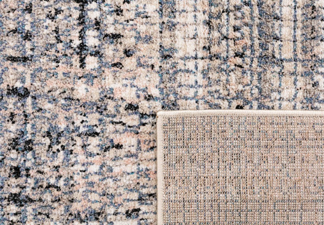 Area rug folded edge showing speckled ivory top and woven beige backing detail