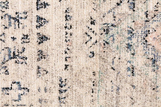 Beige rug surface with scattered dark blue geometric marks and distressed texture