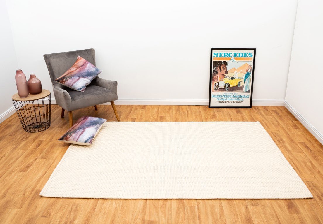 Cream wool rug rectangular with dense textured weave, laid flat on wood floor