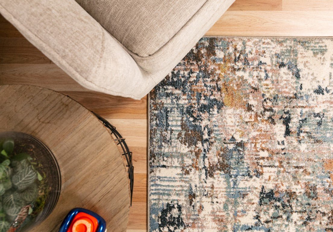 Abstract multi-color area rug on hardwood floor beneath neutral sofa